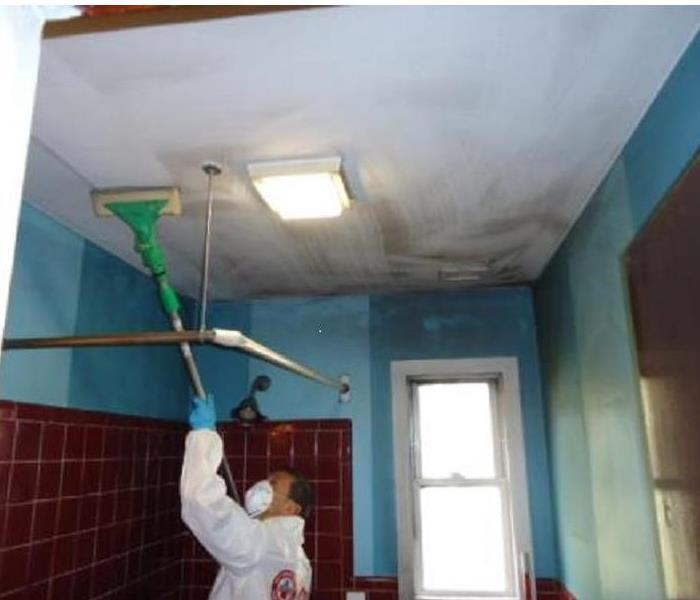 fire technician cleaning soot from ceiling of a bathroom