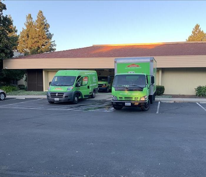 Green SERVPRO vehicles parked on a job site.